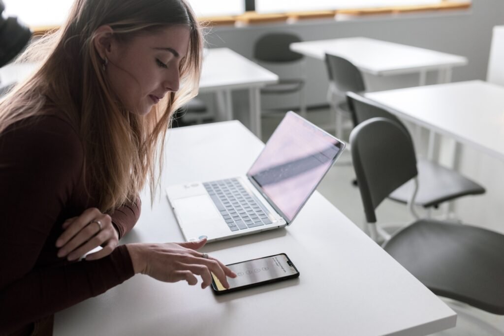 girl at school desk with phone and laptop